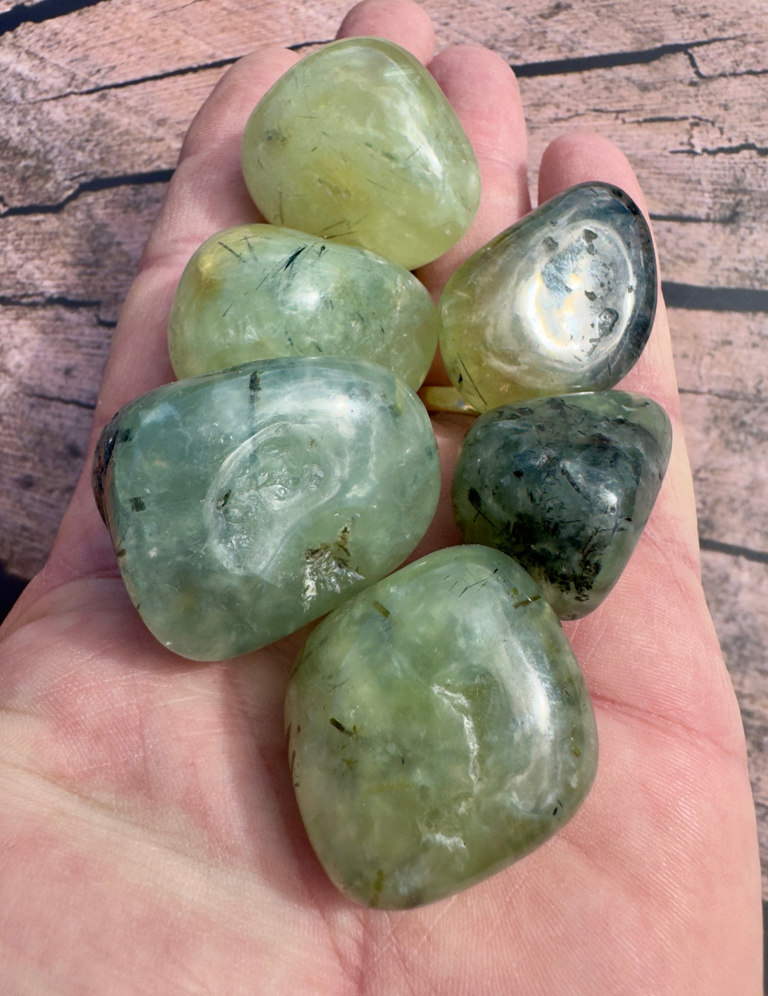 Hand holding polished green Prehnite stones offering unique Prehnite gifts for heart healing and inner peace