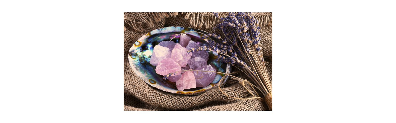 Pieces of raw rose quartz in bowl with lavender on hessian material