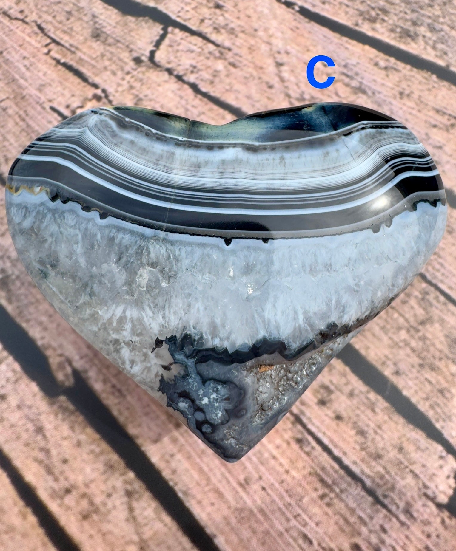 Davinas heart shaped black stripe agate stone with natural layered patterns on wooden surface