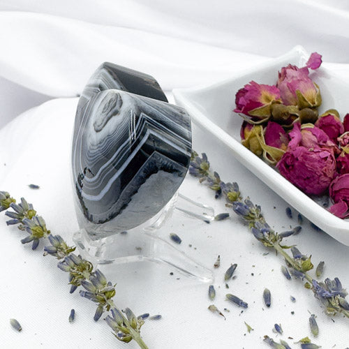 Davinas heart shaped black stripe agate displayed with dried lavender and rose petals on white background