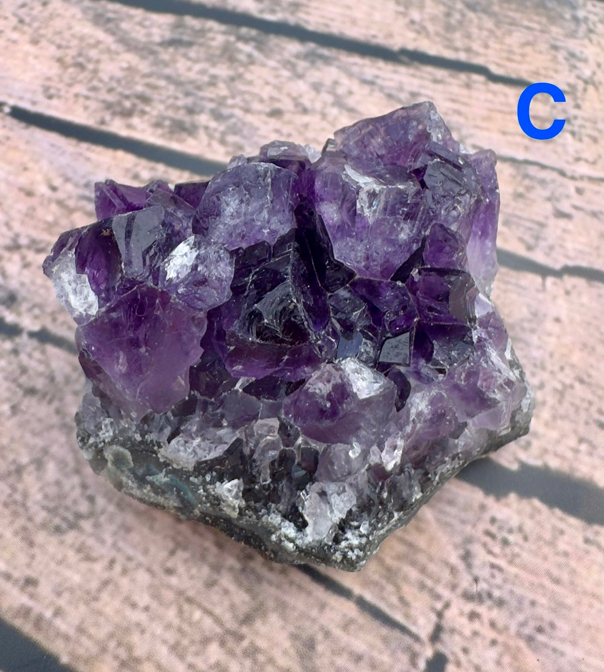 Davinas amethyst raw crystal cluster with deep purple natural quartz crystals on wooden surface