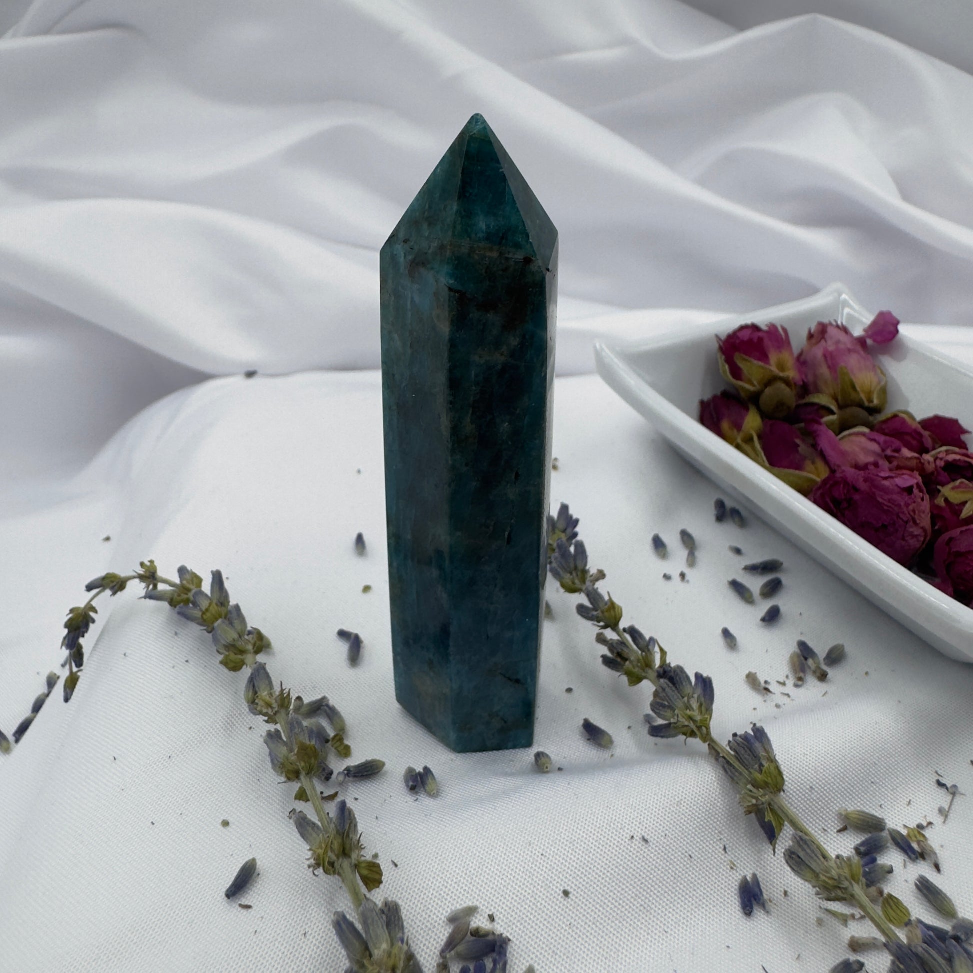 Davinas Apatite Tower Point crystal standing on white fabric with dried flowers around it