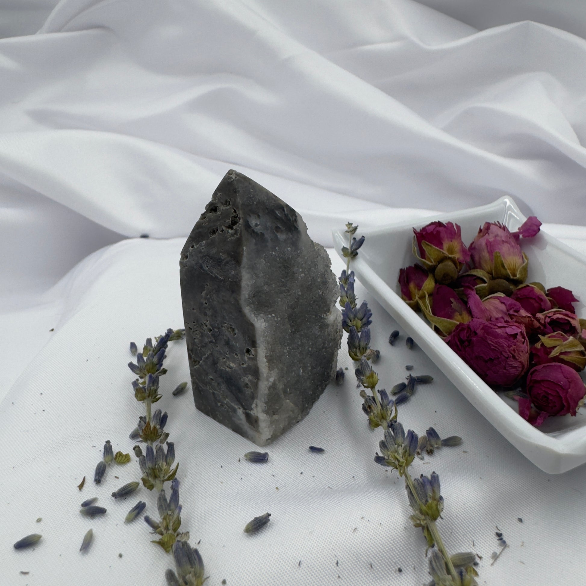 Davinas Black Sphalerite Geode Tower standing upright on white fabric next to dried flowers and lavender sprigs