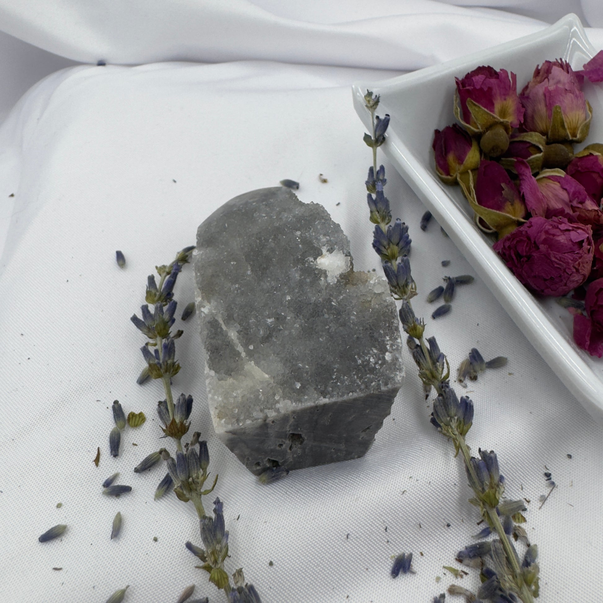 Davinas Black Sphalerite Geode Tower displayed with dried lavender and rose petals on white fabric