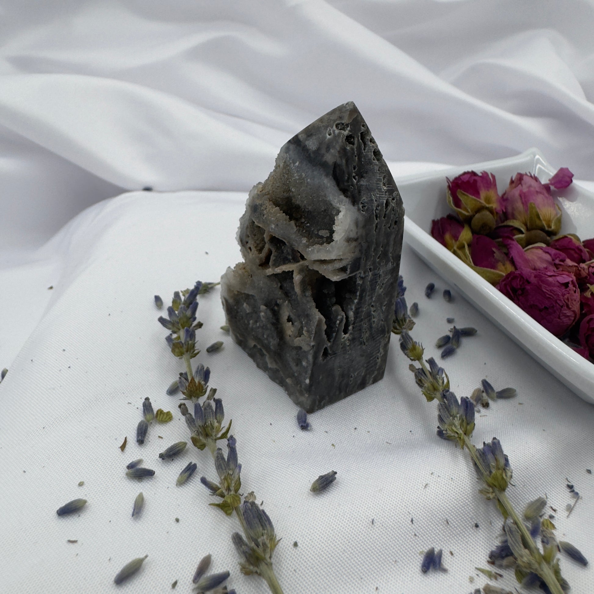 Davinas Black Sphalerite Geode Tower standing on white fabric surrounded by lavender sprigs and dried flowers