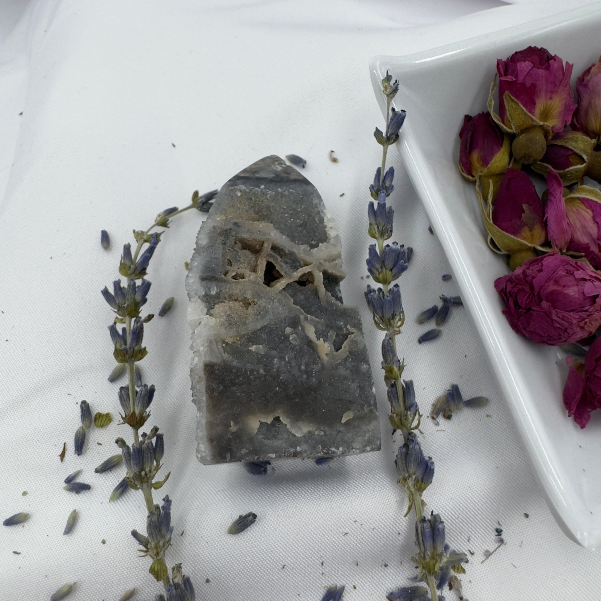 Black Sphalerite Geode Tower surrounded by dried lavender and rose buds on white fabric
