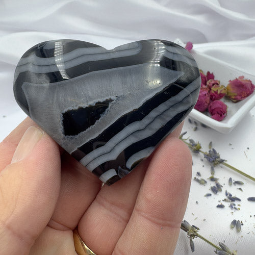 Hand holding a polished Black Stripe Agate Heart stone with black and white banded patterns