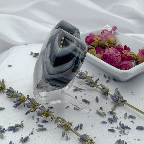 Black Stripe Agate Heart polished stone displayed on clear stand with lavender and dried rose petals