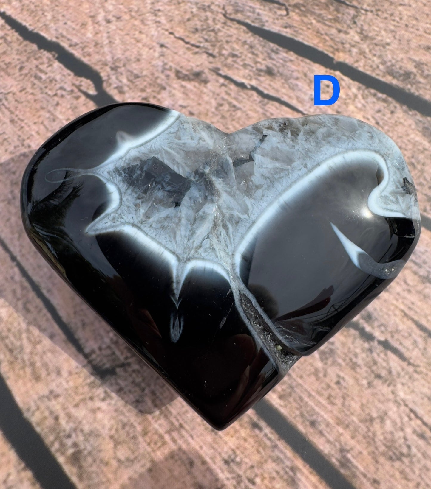 Heart shaped polished black stripe agate stone with glossy surface on wooden background