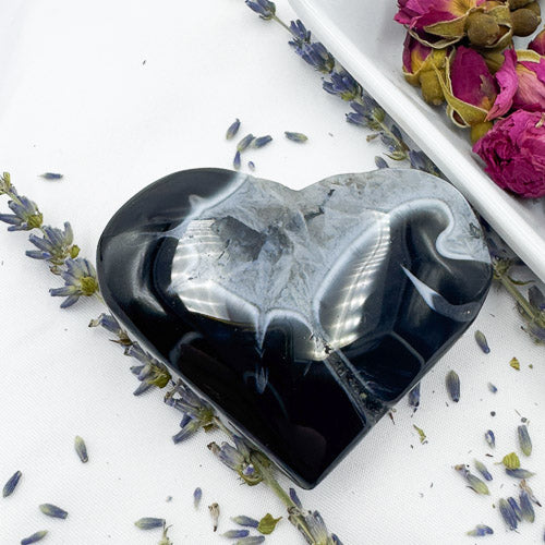 Heart-shaped polished black stripe agate stone with gray and white patterns by Davinas surrounded by dried lavender flowers