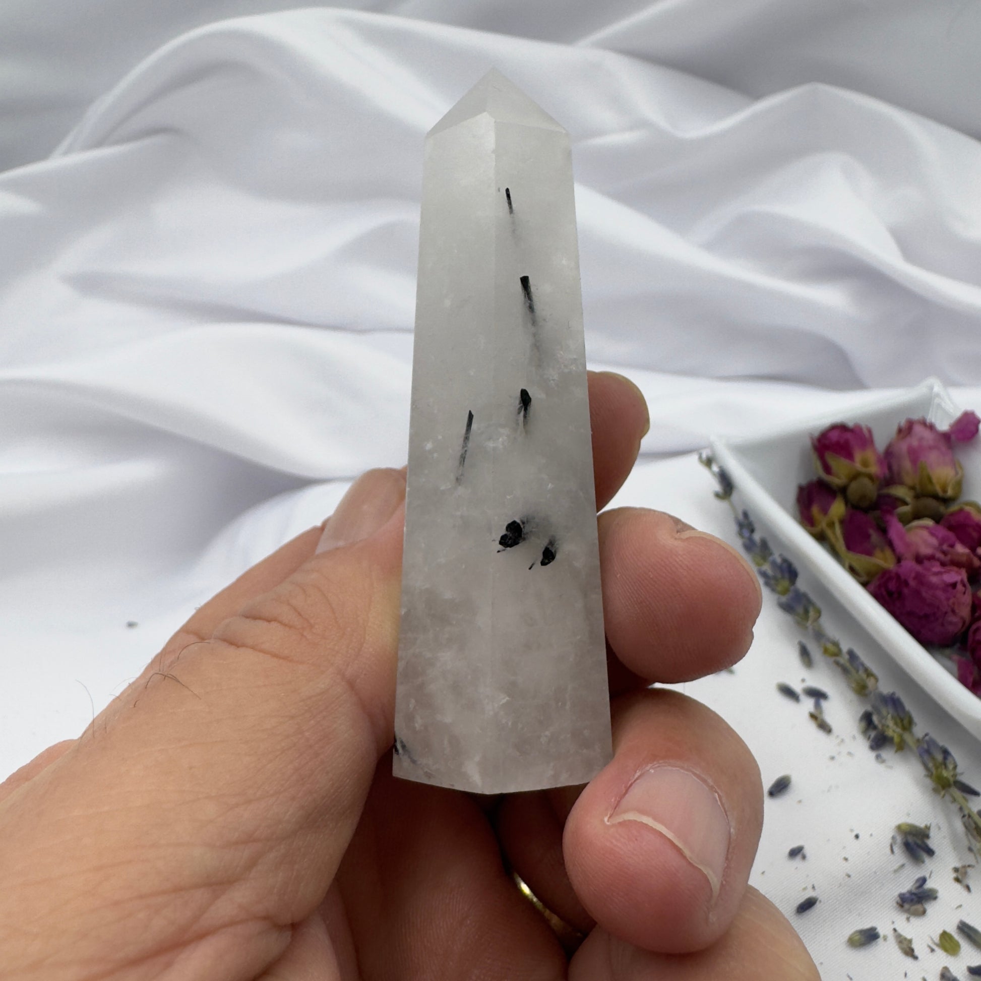 Davinas black tourmaline tower crystal pointed stone held in hand with dried flowers background