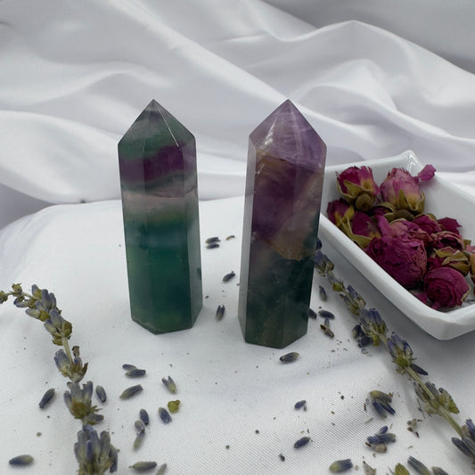 Blue purple green fluorite point crystals standing on white fabric with dried flowers around