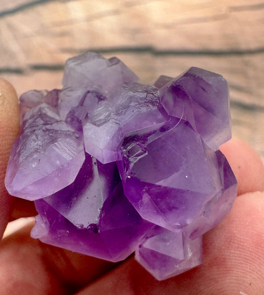 Close-up of purple amethyst crystal mini cluster held between fingers to buy amethyst mini clusters