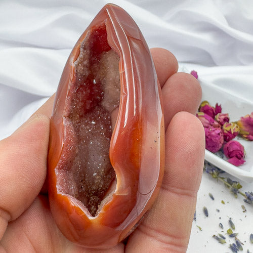 Hand holding a polished Carnelian Geode Druzy Freeform with sparkling crystal interior and smooth outer surface