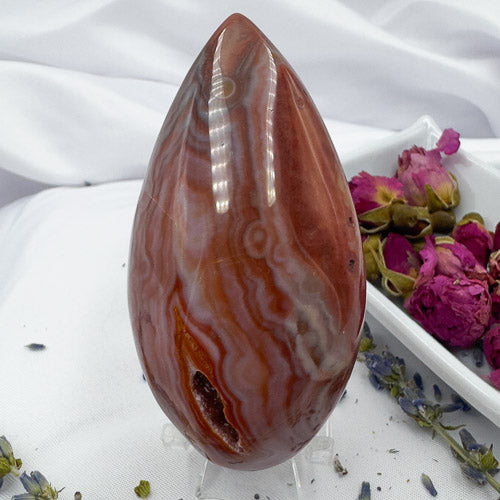 Davinas polished Carnelian Geode Druzy Freeform stone with deep red and white banding on white fabric background