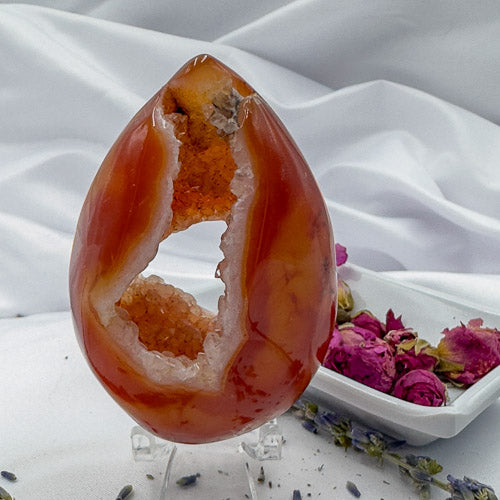 Davinas carnelian geode druzy with vibrant orange crystals and polished exterior on display stand