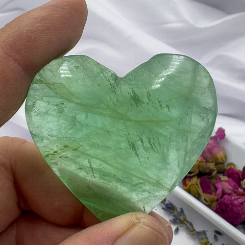 Hand holding a heart-shaped green fluorite stone ideal as a fluorite love gift by Davinas