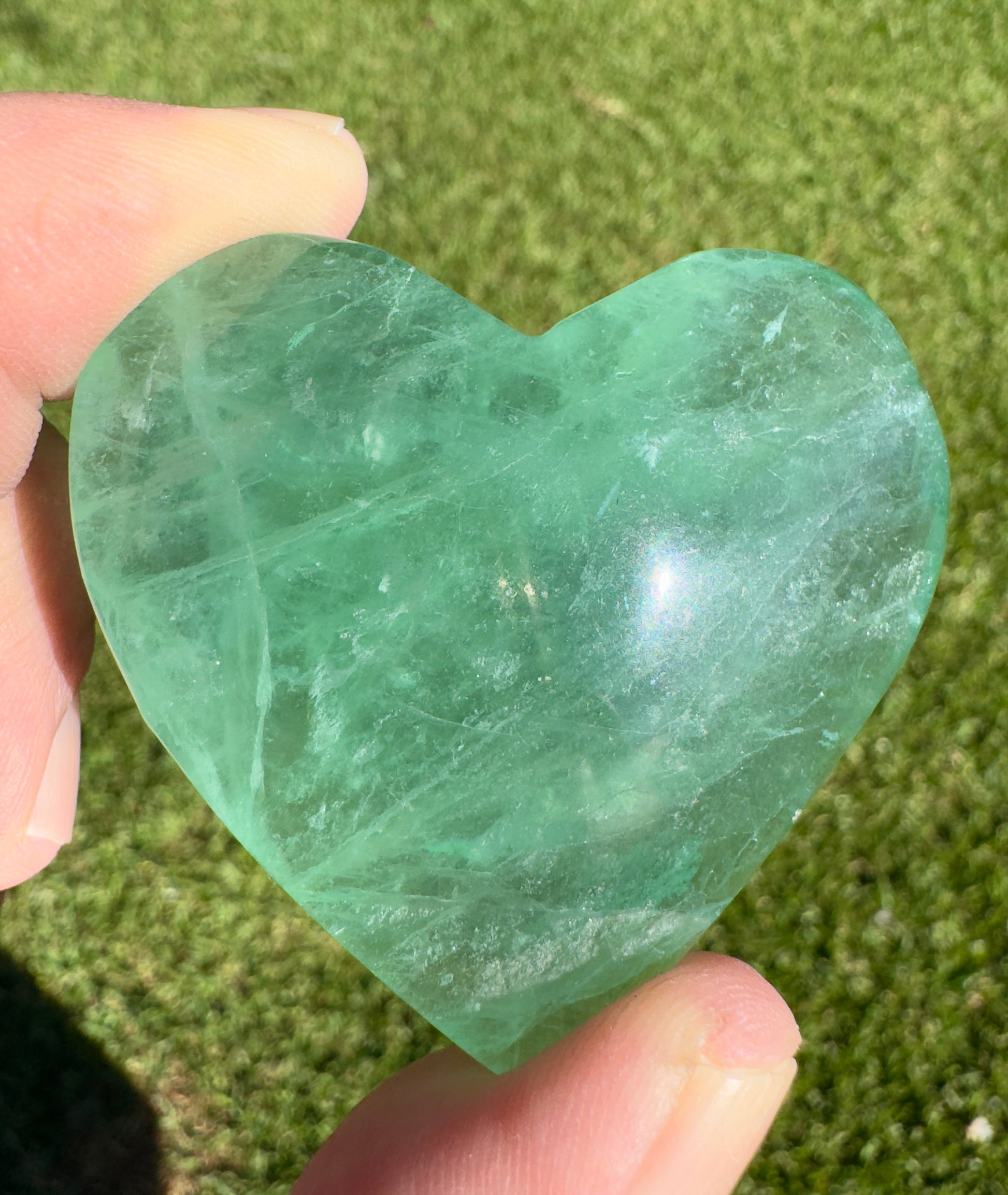 Hand holding a green heart-shaped fluorite stone, ideal as a fluorite love gift from Davinas