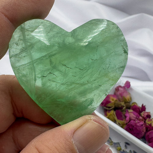Hand holding a green heart-shaped fluorite crystal perfect as a fluorite love gift by Davinas