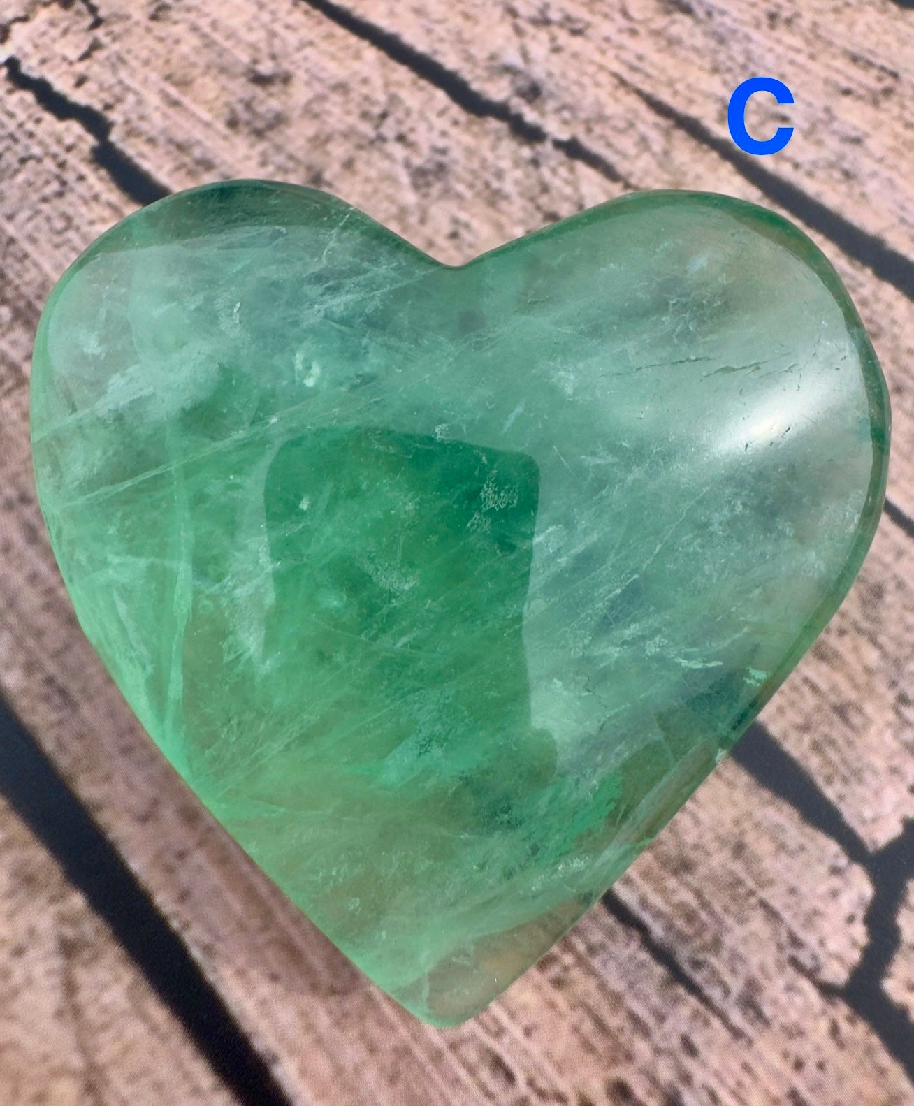 Heart-shaped green fluorite stone on wood surface perfect as a fluorite love gift by Davinas