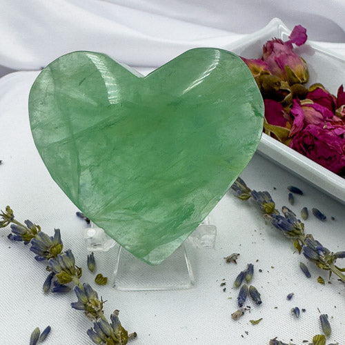 Green heart-shaped fluorite stone displayed with dried flowers as a fluorite love gift by Davinas