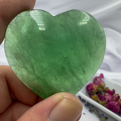 Davinas green fluorite crystal heart held between fingers showing translucent green stone texture