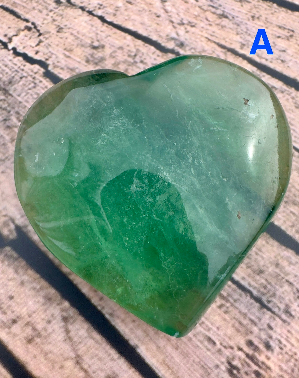 Davinas green fluorite crystal heart with smooth polished surface on textured background