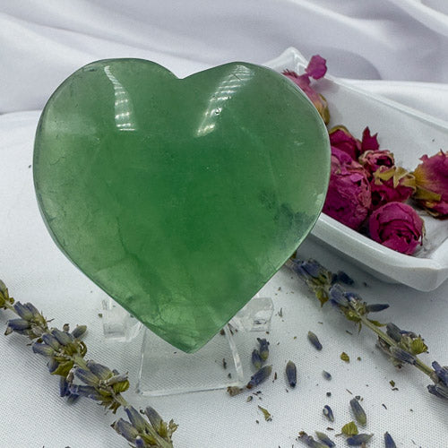Davinas green fluorite crystal heart polished stone displayed on clear stand with dried flowers
