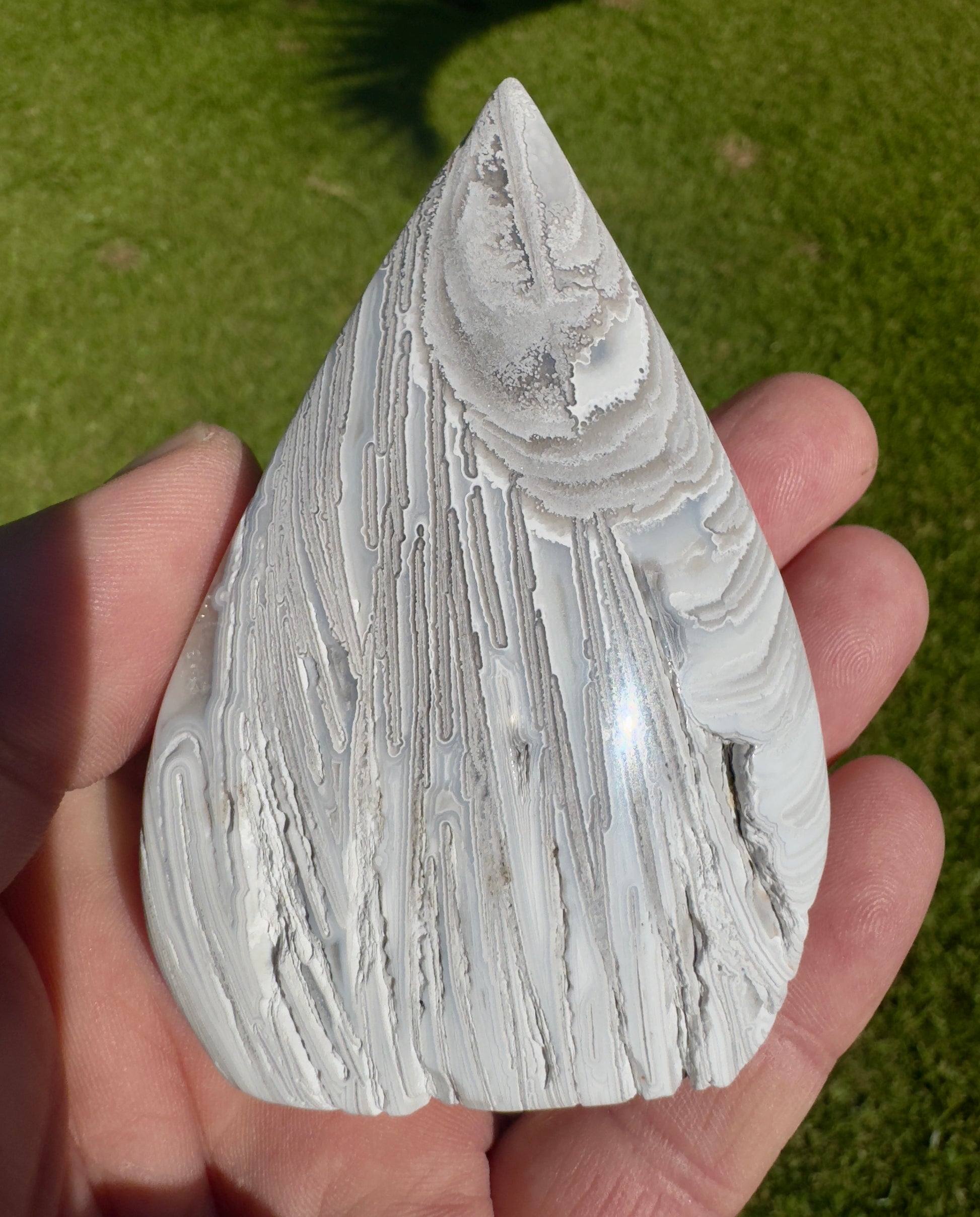 Hand holding a white and gray polished handcrafted agate for collection with intricate natural patterns