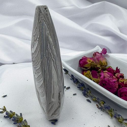 Handcrafted agate for collection displayed upright with dried lavender and pink flowers on white fabric