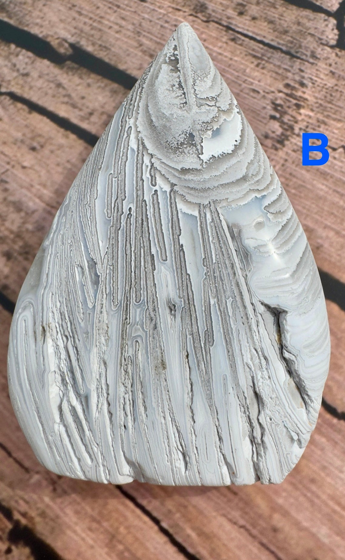 Davinas handcrafted agate for collection stone with white and gray layered patterns on wooden surface