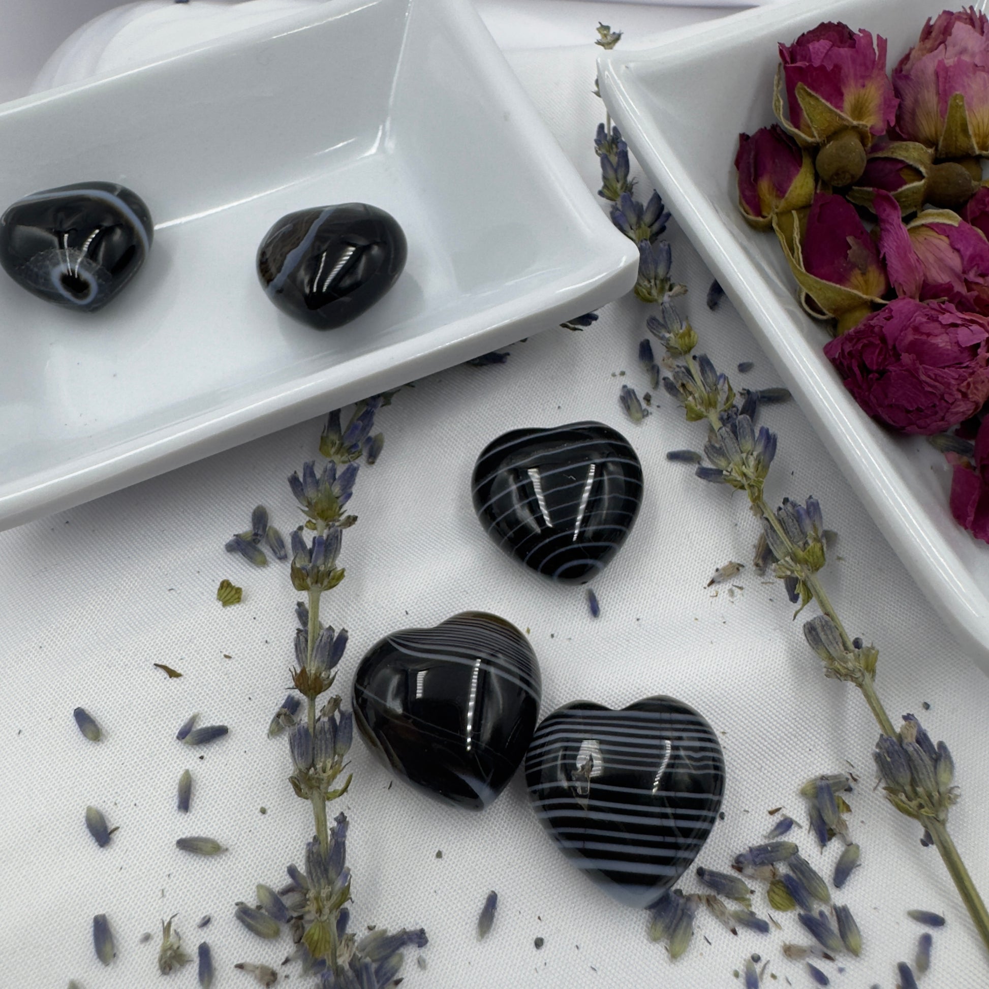 Heart shaped black stripe agate crystal stones displayed with dried lavender and rose petals by Davinas