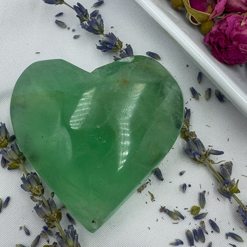 Davinas heart shaped fluorite crystal in green with lavender and dried pink flowers on white background