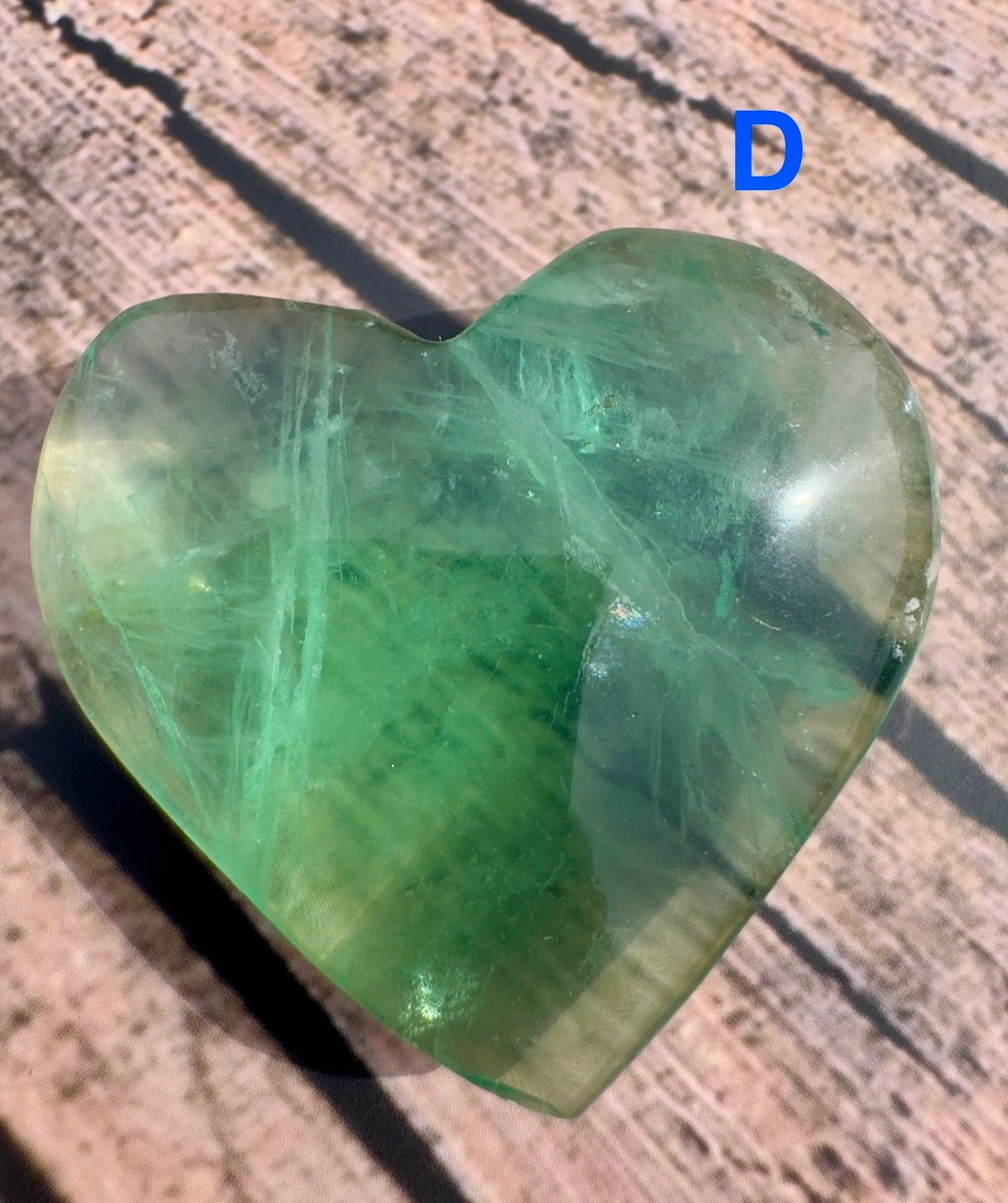 Davinas heart shaped green fluorite crystal polished on rustic wooden surface