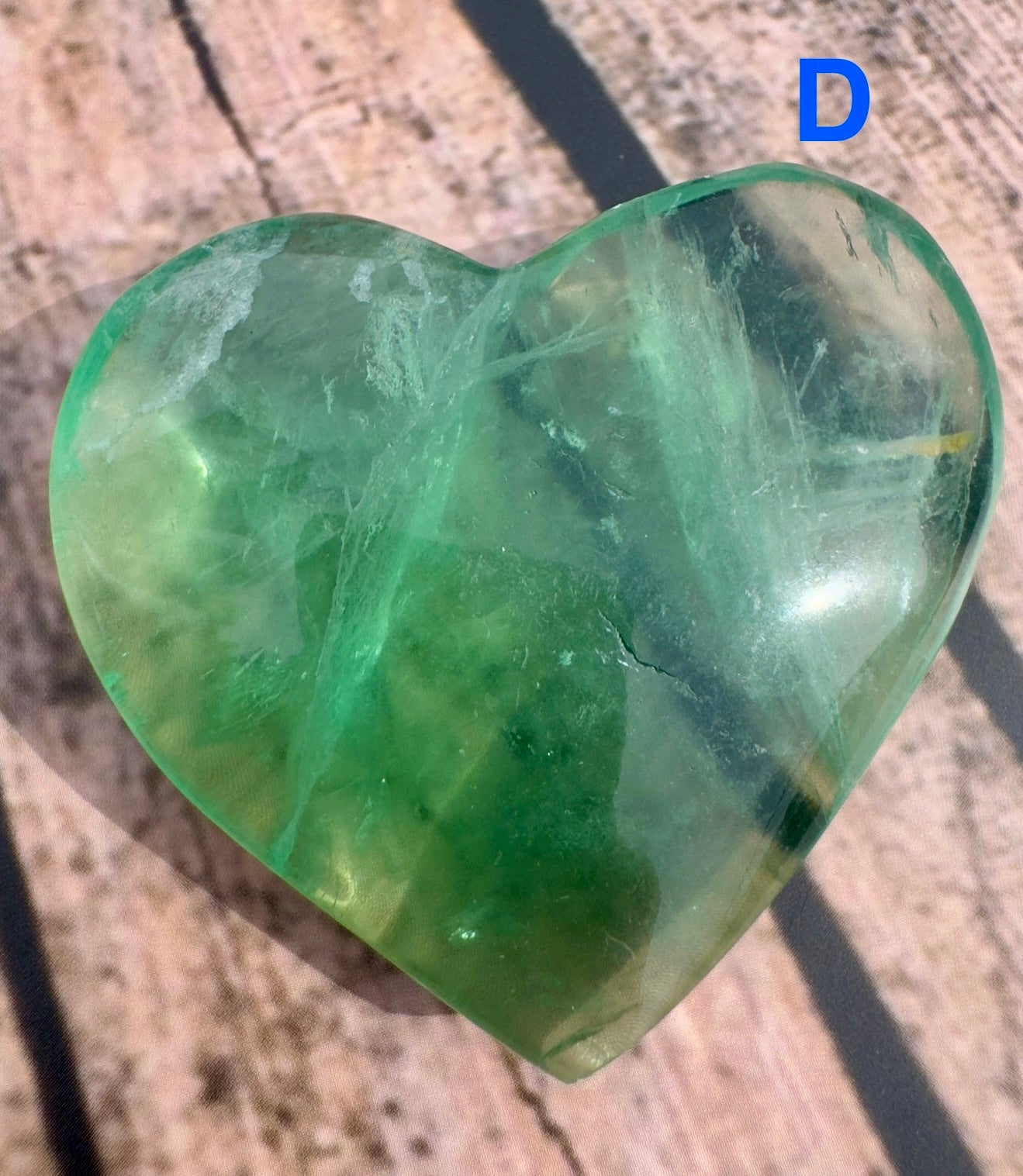 Heart shaped green fluorite crystal polished by Davinas on wooden surface