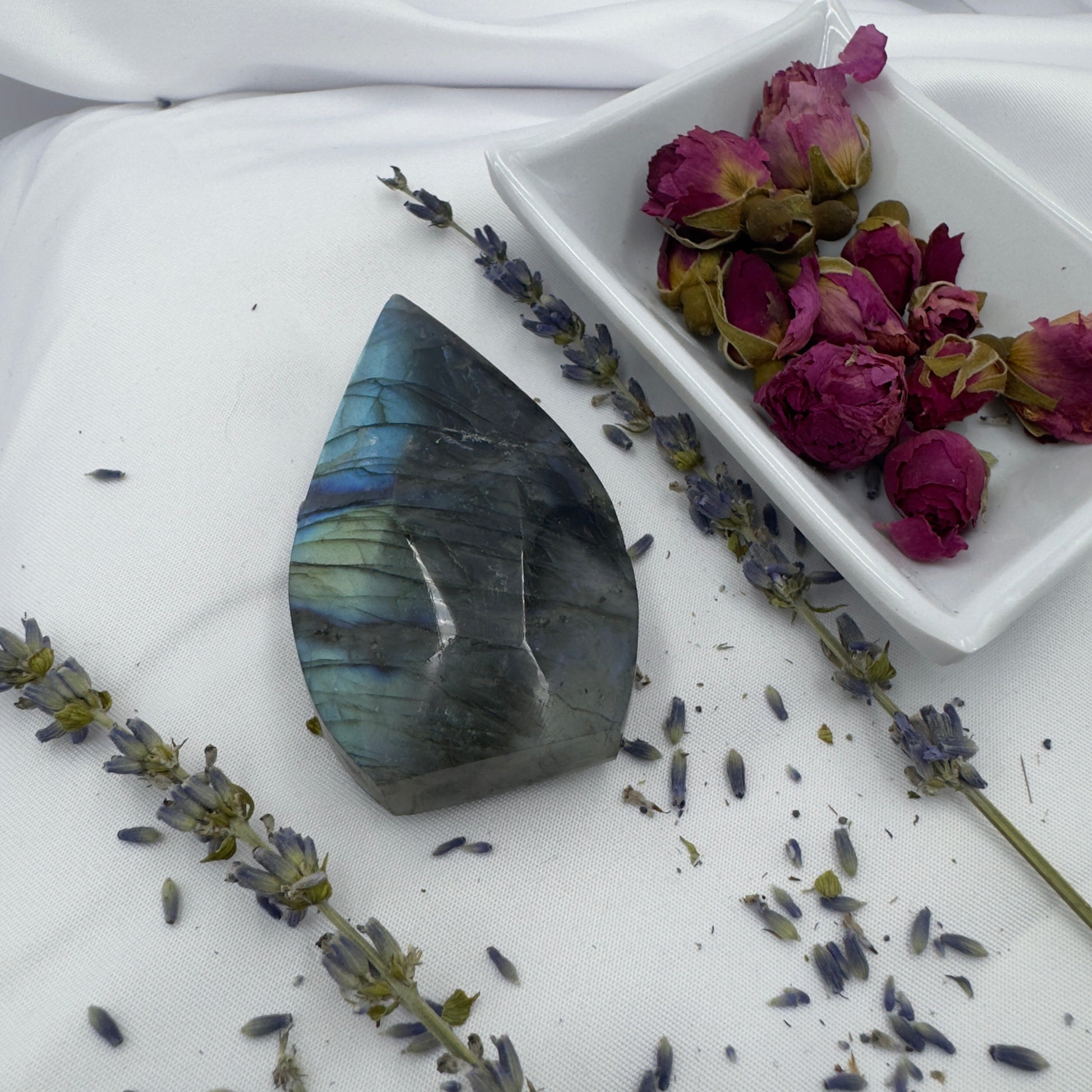 Labradorite freeform crystal with iridescent blue and green hues surrounded by dried lavender and rose buds