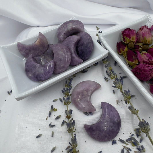Davinas Lepidolite moon crystal crescent stones displayed on white trays with dried lavender and rose petals