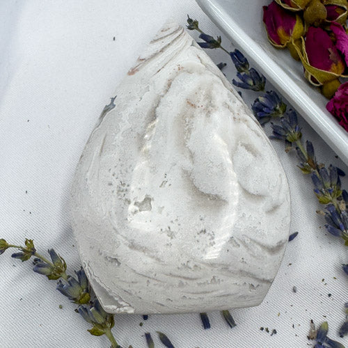 White and gray Morocco agate freeform stone with natural patterns displayed on white fabric with dried flowers