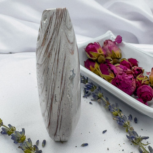 Davinas Morocco agate freeform stone with natural swirling patterns displayed with dried flowers on white fabric