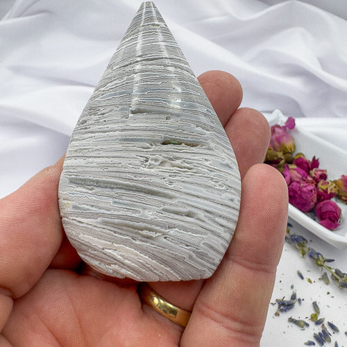 Davinas Morocco agate freeform stone with layered white and gray patterns held in hand