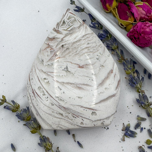 Davinas Morocco agate freeform polished stone with white and light brown patterns on a fabric surface with dried flowers