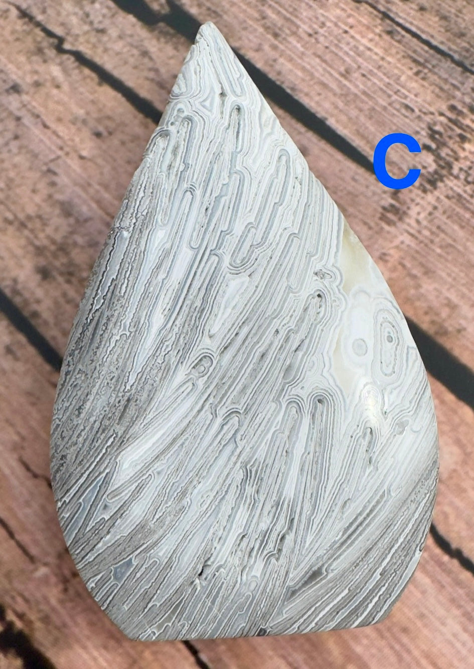 Close-up of Davinas Morocco agate stone with intricate natural patterns on wooden surface