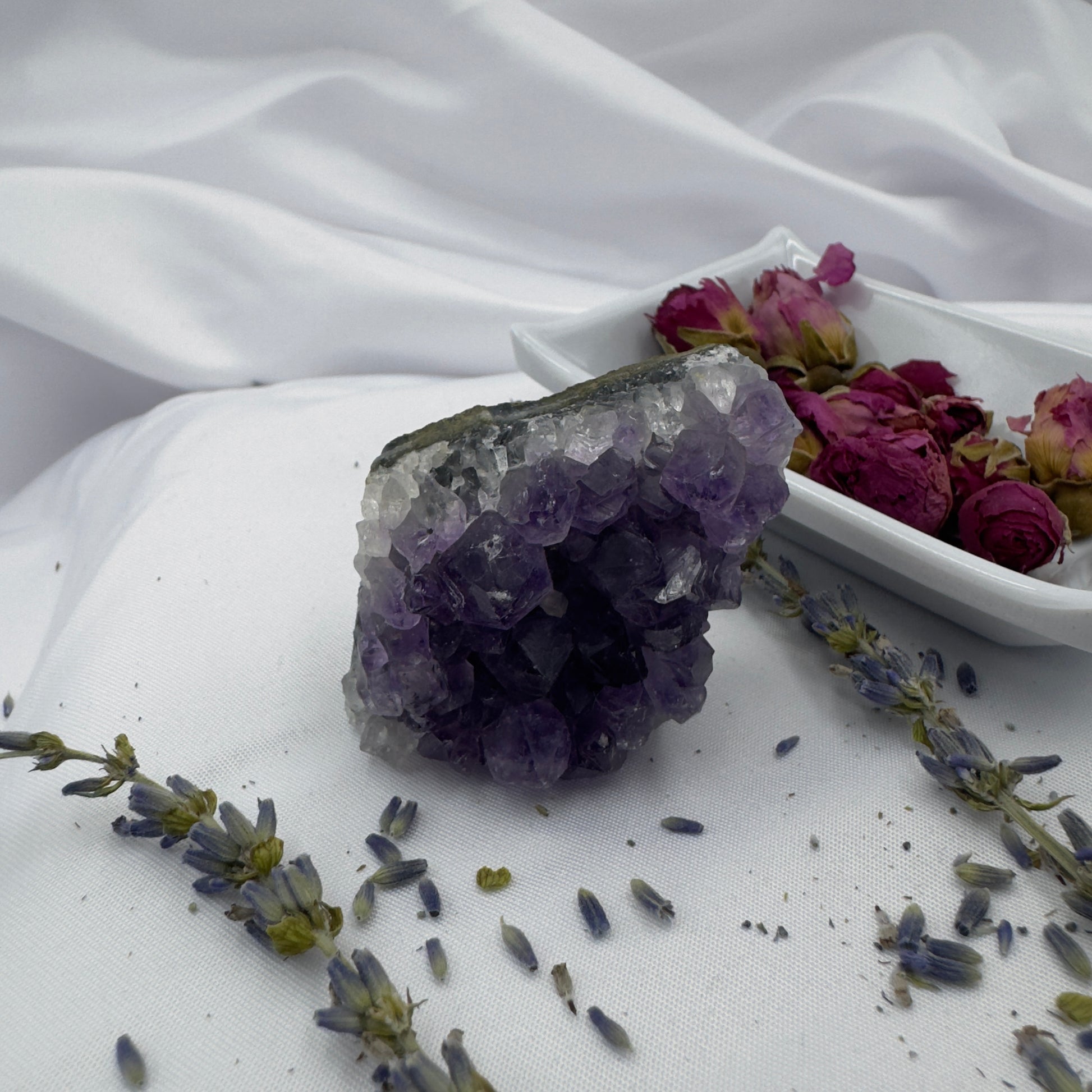 Davinas premium amethyst clusters displayed with dried lavender and rose buds on white fabric