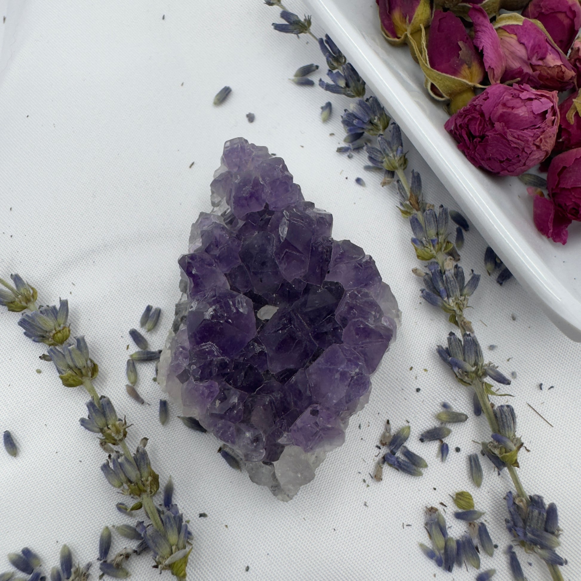 Davinas premium amethyst clusters displayed with dried lavender and rose petals on white fabric