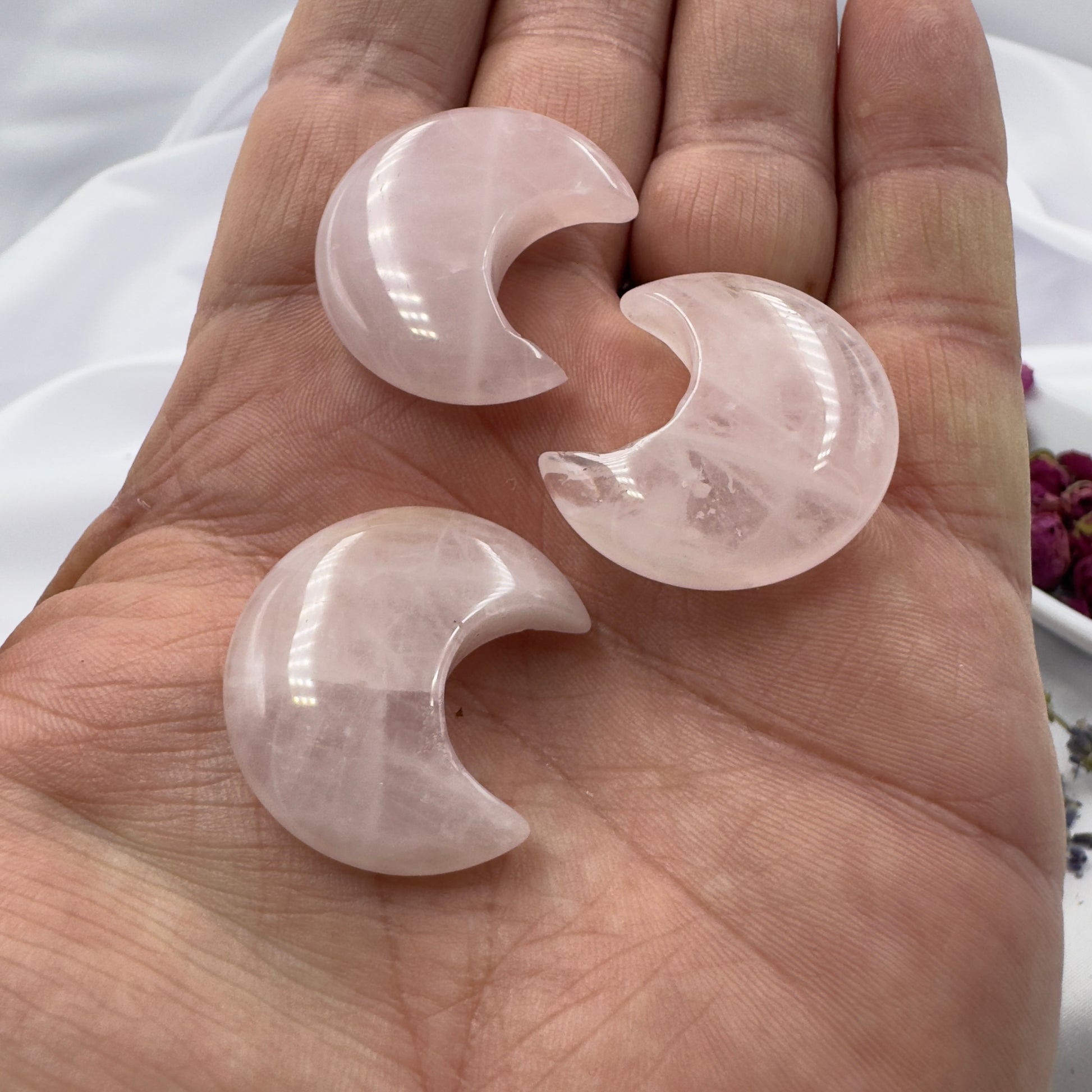 Davinas three polished rose quartz moon crystal pieces held in a hand against a white background