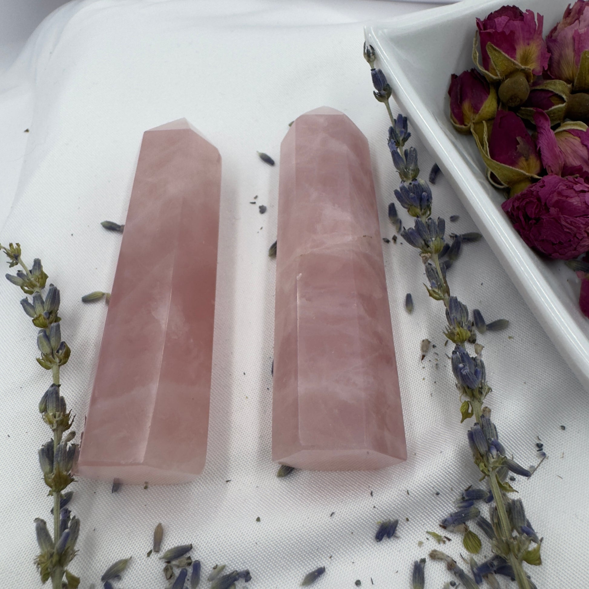 Davinas rose quartz tower point crystals displayed with dried lavender and rose petals on white fabric