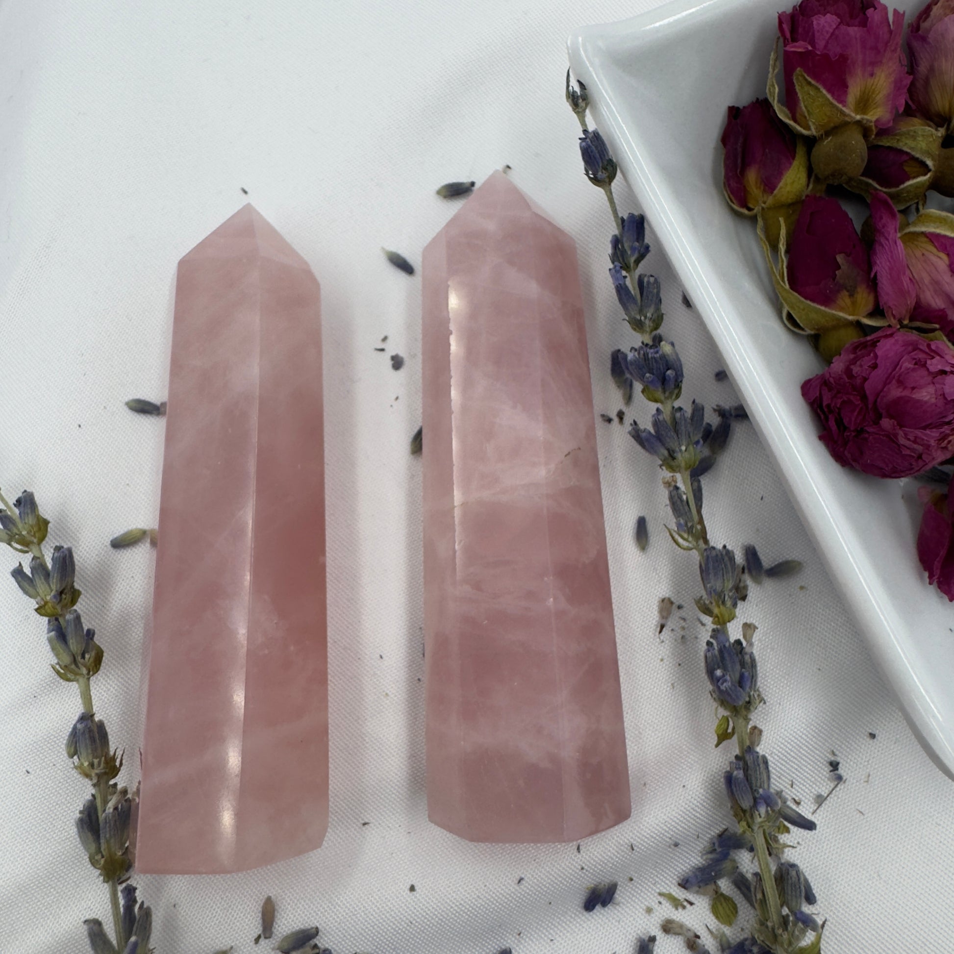Two polished rose quartz tower point crystals from Davinas surrounded by dried lavender and rose buds