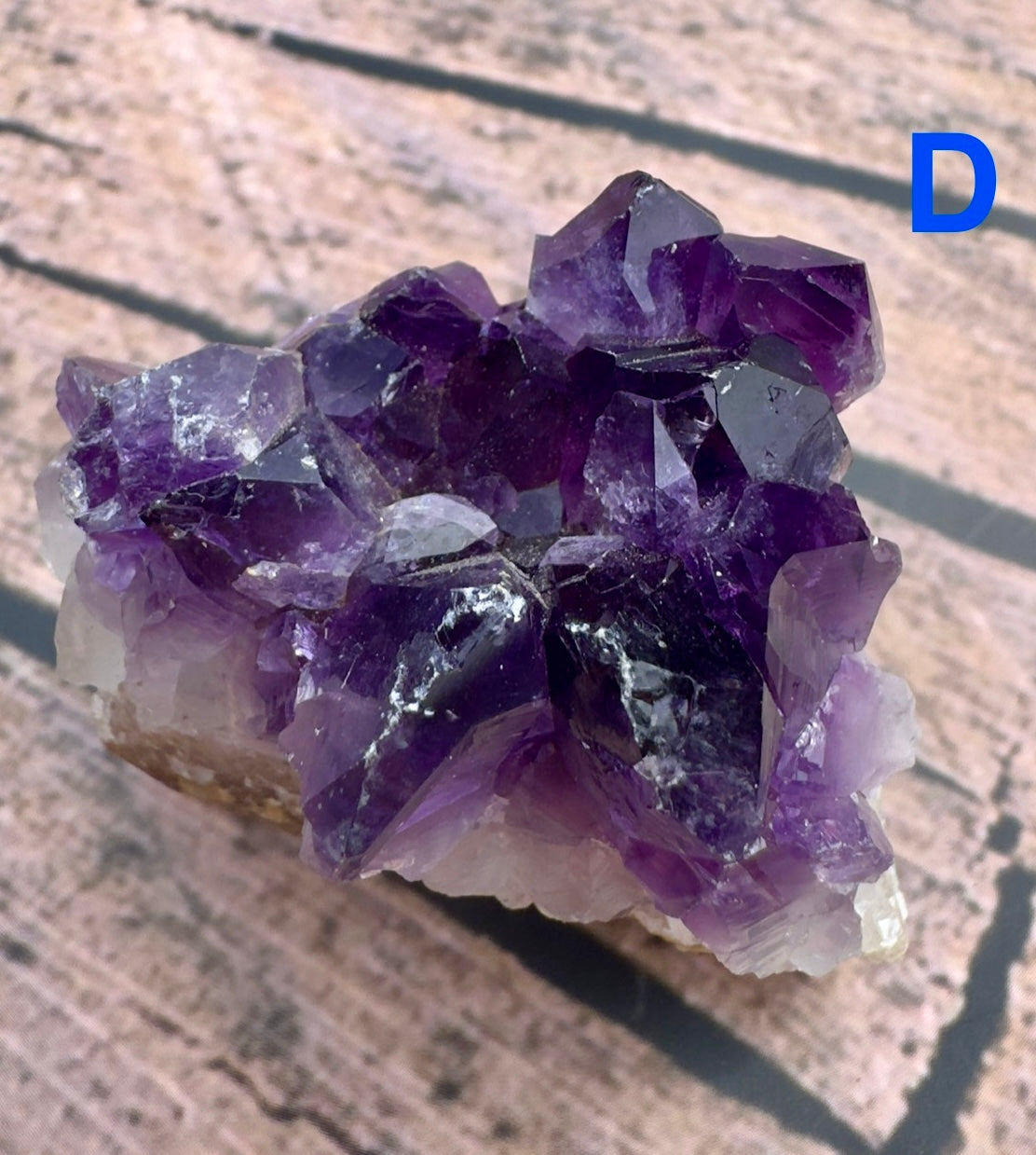 Davinas amethyst raw crystal cluster with deep purple points on a light rock base