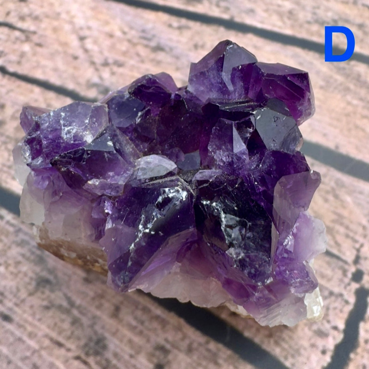 Davinas amethyst raw crystal cluster with deep purple points on a light rock base