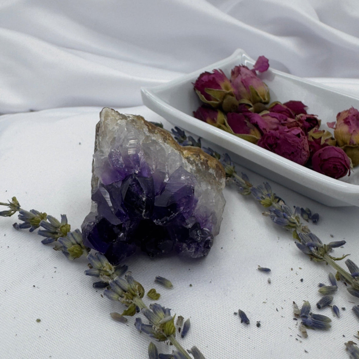 Davinas amethyst raw crystal cluster displayed with dried lavender and rose petals on white fabric